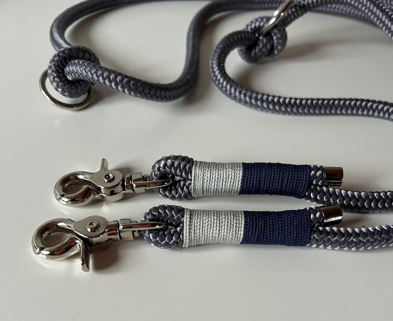 May include: Two gray rope leashes with silver clips and a silver ring. The leashes are striped with white and navy blue.