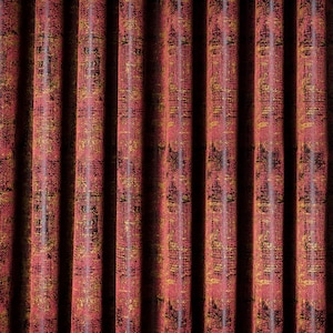 May include: Floor-length pleated curtains in a deep burgundy red fabric featuring a dark, intricate, repeating pattern. Beside the curtains, a framed black and white print depicts a classical marble bust with a horizontal pink stripe across the eyes.