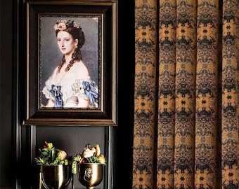 May include: A gold metal decorative stand with a round top and three legs. The stand is holding two gold metal vases with green plants and dried flowers. A framed portrait of a woman in a blue dress with a crown of flowers on her head hangs on the wall behind the stand. The wall is dark brown wood paneling. A patterned curtain is to the right of the stand.