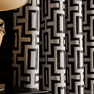May include: Black and white geometric patterned curtains with gold accents. The curtains are made of a textured fabric and have a modern design.