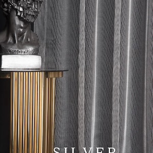 Pode incluir: Cortina prateada com um padr&atilde;o de riscas verticais. A palavra "SILVER" &eacute; exibida em texto branco. Uma mesa lateral dourada e canelada suporta um busto de uma figura cl&aacute;ssica.