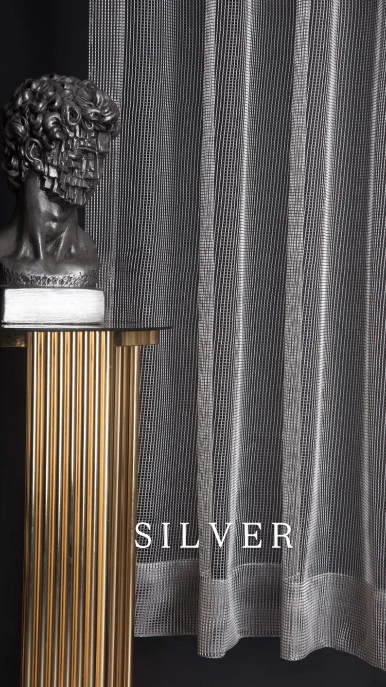 Pode incluir: Cortina prateada com um padr&atilde;o de riscas verticais. A palavra "SILVER" &eacute; exibida em texto branco. Uma mesa lateral dourada e canelada suporta um busto de uma figura cl&aacute;ssica.
