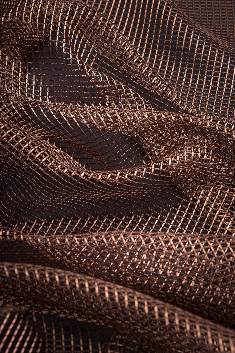 Pode incluir: Close-up de um tecido texturizado, tecido em tons de castanho e cobre. O material tem um padr&atilde;o de grade com um brilho sutil, criando uma sensa&ccedil;&atilde;o de profundidade e dimens&atilde;o. O tecido &eacute; drapeado, mostrando dobras e curvas suaves.