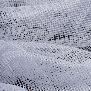 May include: Close-up of white mesh fabric with a grid-like pattern. The fabric is draped and folded, creating shadows and texture. The material appears soft and lightweight, suitable for various craft projects or decorative uses.