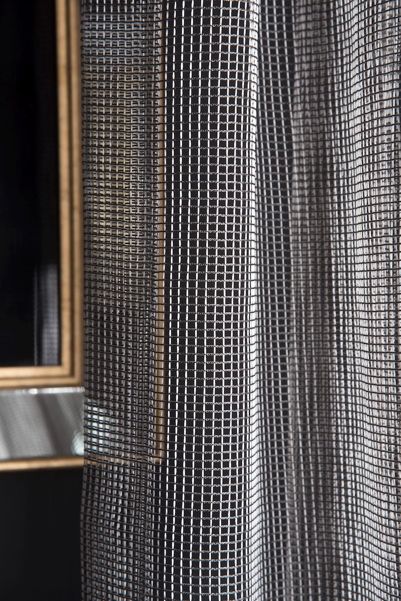Pode incluir: Close-up de uma cortina estampada em preto e branco com um design em forma de grade. A cortina est&aacute; pendurada ao lado de um espelho com moldura dourada. O padr&atilde;o &eacute; feito de pequenos quadrados.