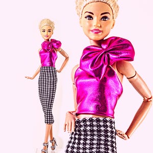 May include: Two fashion dolls with blonde hair styled in short cuts. Each doll wears a metallic hot pink sleeveless top featuring a large bow detail on the shoulder, paired with a black and white houndstooth print pencil skirt.