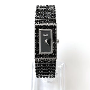 Puede incluir: Un reloj de pulsera rectangular negro con esfera negra y agujas plateadas. La esfera muestra las letras "D&G" y una flecha plateada. La correa del reloj está hecha de piedras negras.