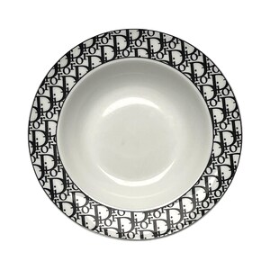 May include: White ceramic bowl with a black and white repeating pattern around the rim. The pattern consists of the letters "D" and "I" in a repeating design. The bowl has a simple, elegant design.