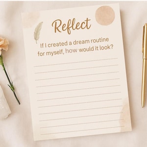Puede incluir: Una página de diario beige con la palabra "Reflect" y la pregunta "Si creara una rutina de ensueño para mí, ¿cómo sería?" junto a un bolígrafo dorado, una flor y un cristal.
