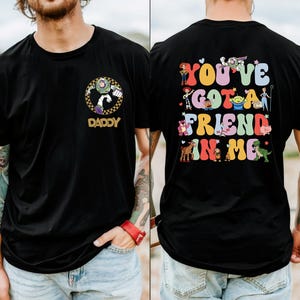 May include: Black t-shirt with a Buzz Lightyear graphic and the word "DADDY" on the front. The back of the shirt has the phrase "YOU'VE GOT A FRIEND IN ME" with colourful Toy Story characters.