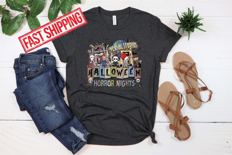 Puede incluir: Una camiseta gris oscuro con un gr&aacute;fico de Universal Studios Halloween Horror Nights con personajes de pel&iacute;culas de terror. El gr&aacute;fico incluye el texto "Universal Studios Halloween Horror Nights".