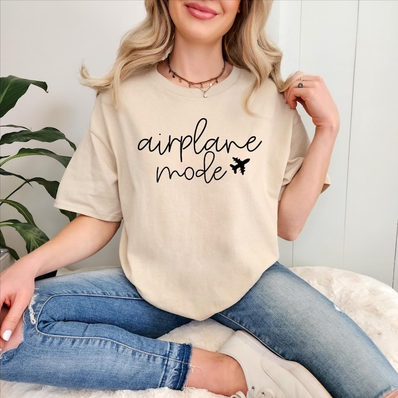 May include: A beige t-shirt with the text "airplane mode" and a small airplane graphic printed on the front.