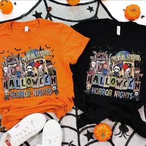 Puede incluir: Dos camisetas con un dise&ntilde;o de Halloween Horror Nights con el logotipo de Universal Studios y personajes de pel&iacute;culas de terror. Las camisetas son naranja y negra.