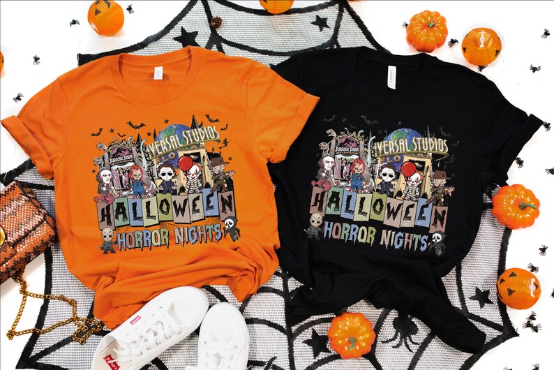Puede incluir: Dos camisetas con un dise&ntilde;o de Halloween Horror Nights con el logotipo de Universal Studios y personajes de pel&iacute;culas de terror. Las camisetas son naranja y negra.