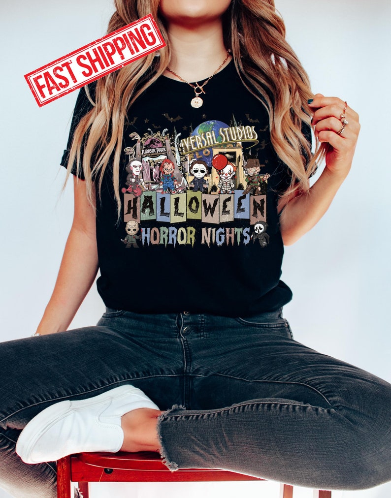 Puede incluir: Camiseta negra con un gr&aacute;fico de varios personajes de pel&iacute;culas de terror frente a un letrero de Universal Studios Halloween Horror Nights. Los personajes incluyen a Freddy Krueger, Jason Voorhees, Michael Myers, Pennywise, y m&aacute;s.