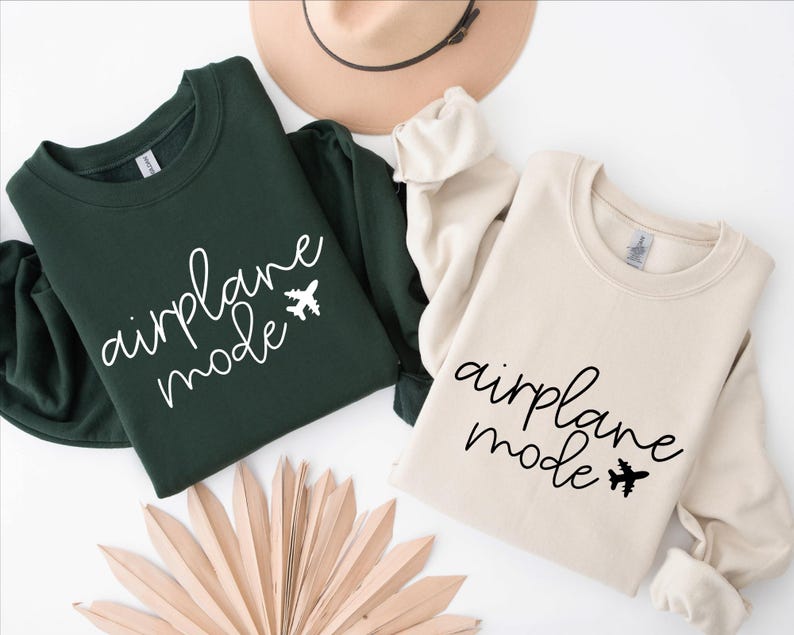 May include: Two sweatshirts, one green and one beige, with the text "airplane mode" and a small airplane graphic printed on the front.