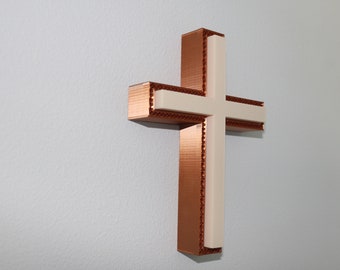 May include: A copper-colored cross with a white center. The cross is made of a textured material and has a modern design.