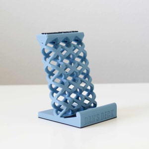 May include: A light blue phone stand with a geometric design and the text "DAN'S DECK" on the base.