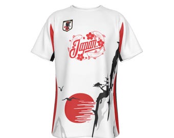 Puede incluir: Camiseta blanca con un diseño de inspiración japonesa en rojo, negro y gris. La camiseta presenta un sol rojo, una cordillera, un árbol estilizado y la palabra "Japón" en una fuente estilizada.