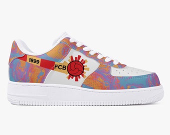 Puede incluir: Zapatillas blancas de caña baja con un diseño abstracto colorido que presenta un logotipo de balón de fútbol rojo y amarillo con el texto "FCB 1899".