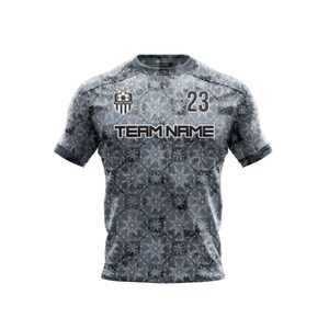 May include: Gray soccer jersey with a white and black snowflake pattern. The jersey has a team logo on the left chest and the number 23 on the right chest. The text "TEAM NAME" is printed below the logo.