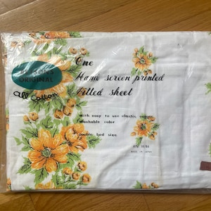 May include: A white fitted sheet with a floral pattern in shades of yellow and green. The sheet is made of all cotton and features a hand-screen printed design. The packaging includes the text "Betson's Original One Hand Screen Printed Fitted Sheet All Cotton With easy to use elastic corner Washable color Double bed size RN 16704 Made in Japan."