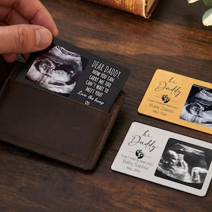 May include: Three rectangular metal wallet cards featuring ultrasound images. One black card reads Dear Daddy, now you can carry me too, can't wait to meet you! Love the bump. Gold and silver cards read hi Daddy, I can't wait to meet you!