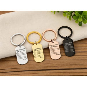 May include: Four metal keyrings with engraved messages. The keyrings are silver, gold, rose gold, and black. Each keyring has a rectangular tag with the words "TO MY DAUGHTER Little Reminders" or "TO MY SON Little Reminders" and a list of affirmations.
