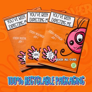 Op de afbeelding: Drie oranje verpakkingen met de tekst "You've Been Expecting Me." De verpakkingen hebben een cartoonhand met de tekst "Sticky Nostalgia Joy!" en "Vinyl" of "Glossy Stickered Paper". De verpakkingen bevinden zich op een feloranje achtergrond met de tekst "Stuck All Over" en "100% Recyclable Packaging".