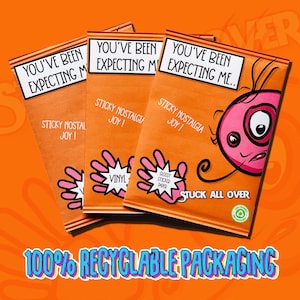 May include: Three orange packets with the text "YOU'VE BEEN EXPECTING ME" and "STICKY NOSTALGIA JOY!". Each packet features a pink hand graphic and a cartoon face. The bottom text reads "100% RECYCLABLE PACKAGING".