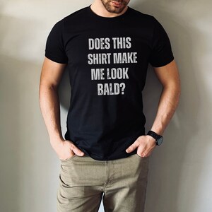 May include: A black t-shirt with the text "Does this shirt make me look bald?" printed in white.
