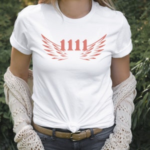 May include: White t-shirt with a red graphic of wings and the number 1111.