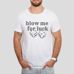 May include: White t-shirt with the text "blow me for luck" and two dice printed on the front.