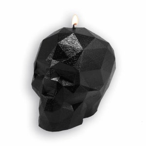 May include: A black geometric skull candle with a lit wick. The candle is made of wax and has a detailed, faceted design.