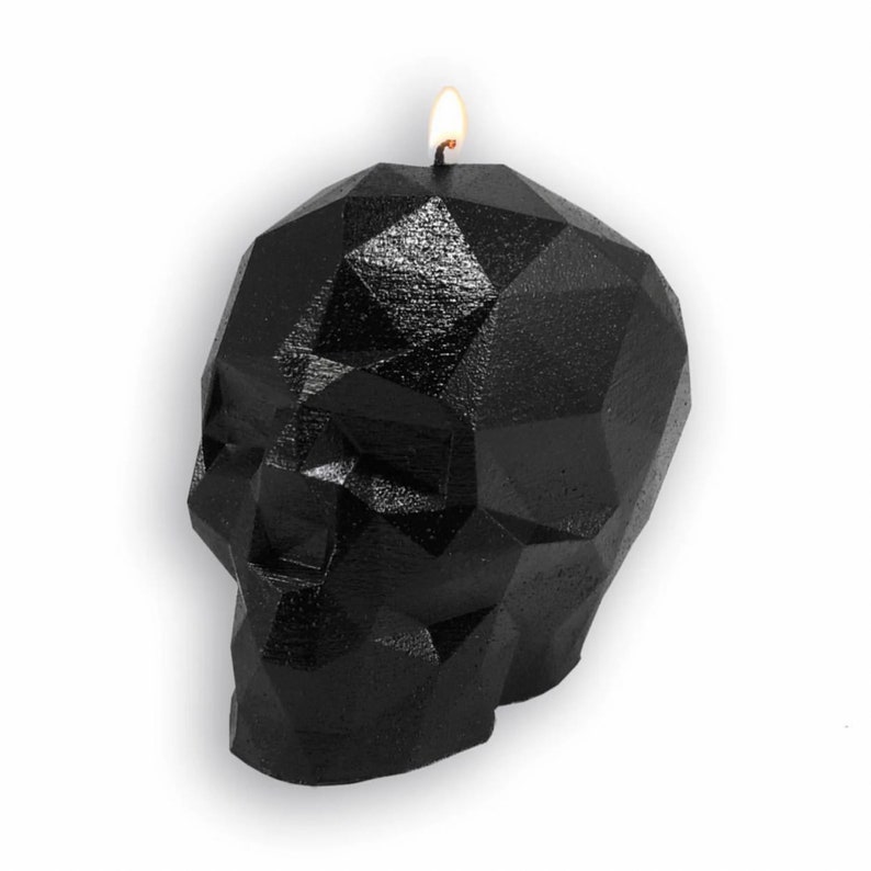 May include: A black geometric skull candle with a lit wick. The candle is made of wax and has a detailed, faceted design.