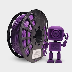 May include: A purple filament spool labeled "Mystic Purple" next to a 3D-printed purple robot. The filament is wound around a black spool. The robot has a square head and body with outstretched arms.