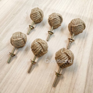 May include: Six brown rope cabinet knobs with gold screws. The rope is tied in a knot to form the knob.