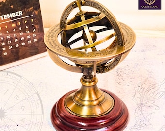 Op de afbeelding: Een messing hemelglobe met een houten voet. De globe staat op een standaard en heeft een kompasroos en dierenriemtekens rond de evenaar. De globe is een decoratief item en is perfect voor een bureau of boekenplank.
