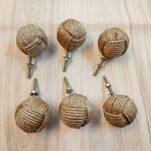 Pode incluir: Seis botões de armário de corda marrom com um design de nó e parafusos de metal prateados.