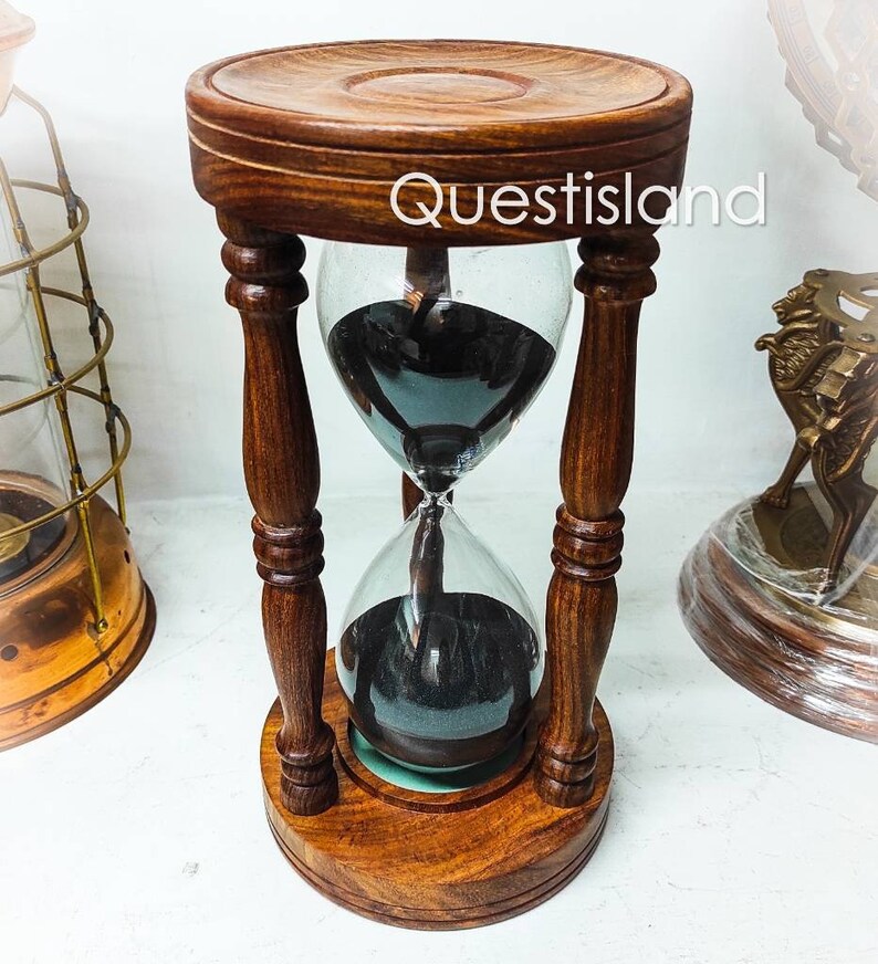 May include: A wooden hourglass with black sand, featuring a dark wood base and pillars. The hourglass is approximately 10 inches tall.