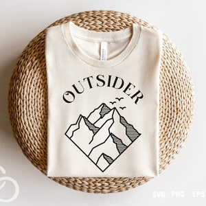 May include: A white t-shirt with a black graphic design of mountains and the word "OUTSIDER" in a bold font.