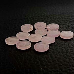 Peut inclure: Une collection de 12 cabochons ronds en pierre précieuse rose pâle. Les cabochons sont lisses et polis, avec une apparence légèrement translucide.