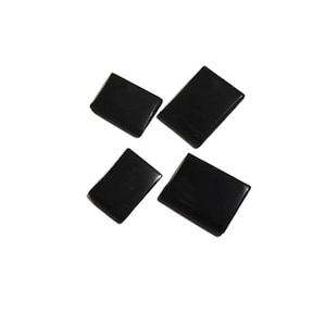Peut inclure: Quatre carreaux rectangulaires noirs, possiblement en céramique ou en pierre, disposés en forme de croix sur un fond blanc.