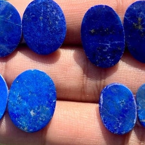Op de afbeelding: Acht ovale lapis lazuli cabochons in verschillende tinten blauw met vlekken van gouden pyriet.