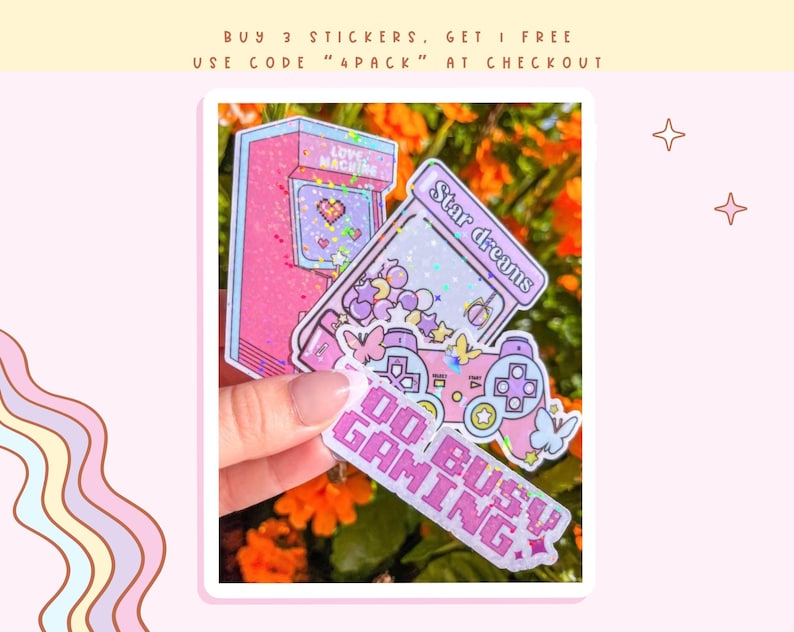 May include: Four pink and purple holographic stickers with glitter. The stickers feature a video game controller, a retro arcade game, a star, and the text "Do Busy Gaming".