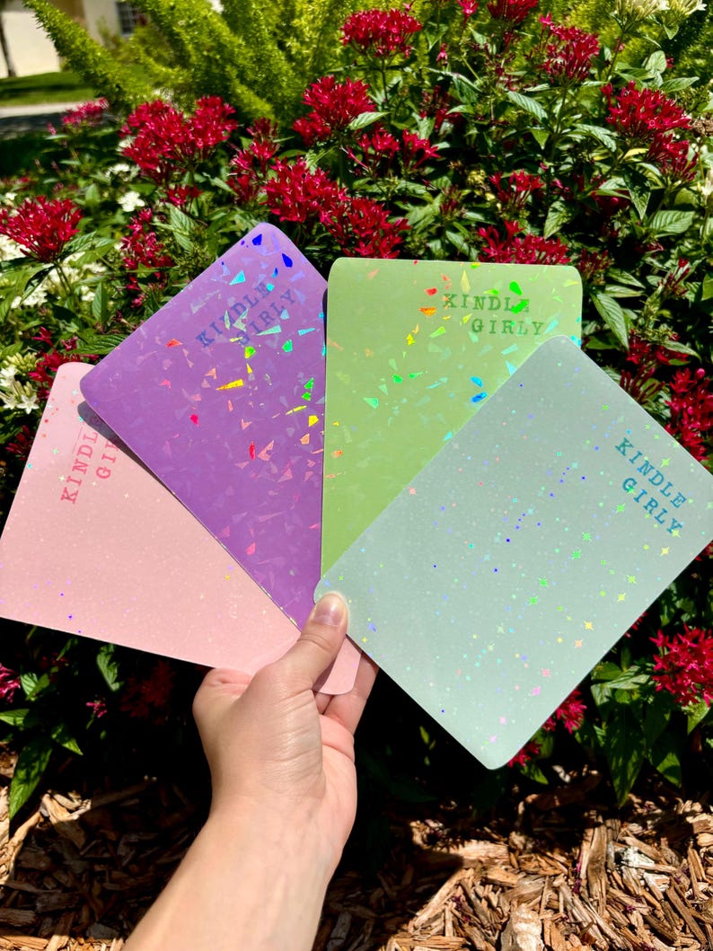May include: Four different colored notebooks with a holographic finish and the text "Kindle Girly" printed on each.
