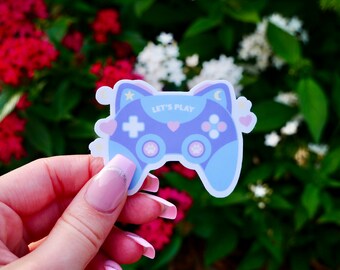 Könnte beinhalten: Ein blauer und rosa Katzen-Videospiel-Controller-Aufkleber mit dem Text "Let's Play".
