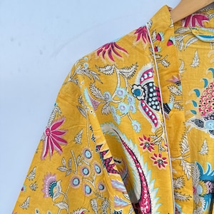 May include: A yellow floral print robe with a white trim. The robe has a long sleeve and a tie closure.