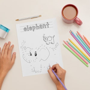 K&ouml;nnte beinhalten: Ein Kind verbindet die Punkte, um einen Elefanten auf einem wei&szlig;en Blatt Papier zu zeichnen. Das Papier hat oben das Wort "Elefant" geschrieben. Das Kind verwendet einen lila Stift, um die Punkte zu verbinden. Auf dem Tisch liegen auch verschiedene farbige Stifte und eine Tasse Kaffee.