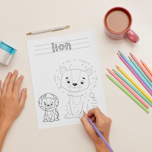 K&ouml;nnte beinhalten: Eine schwarz-wei&szlig;e Punkt-zu-Punkt-Malvorlage mit einem L&ouml;wen und einem L&ouml;wenjungen. Die Seite hat das Wort "L&ouml;we" oben geschrieben. Eine Hand h&auml;lt einen lila Stift und verbindet die Punkte auf der Seite.